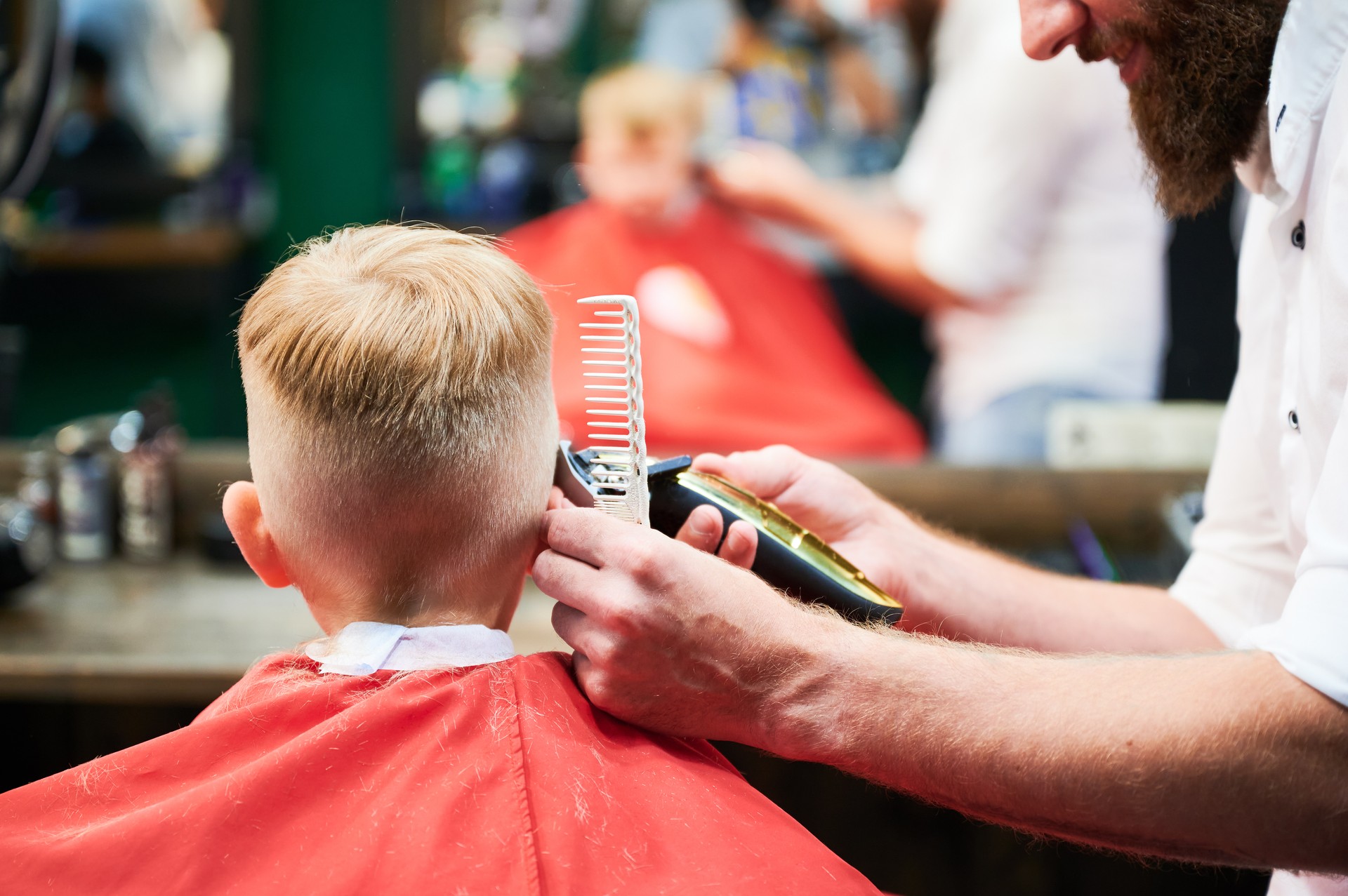 Barber using comb and shaver to cut hair.